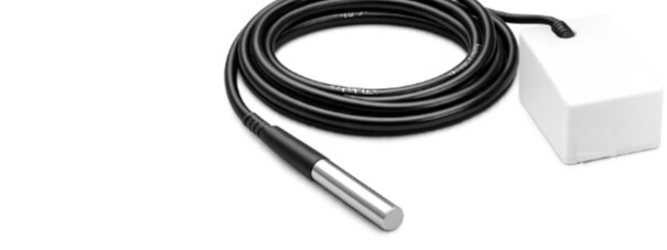 Coiled black pipe-temperature probe with a metal tip, wired to a white transmitter.